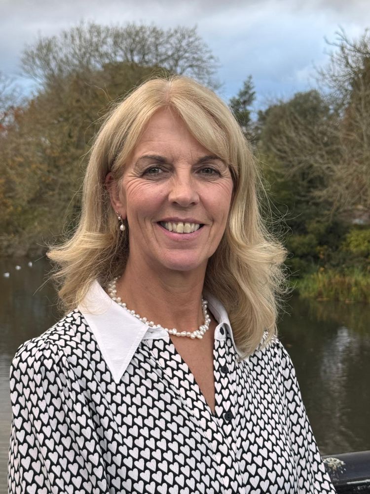 Close up of a woman standing on a bridge with a river and countryside in the background
